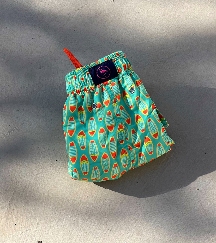 Bañador para niños Surfish con estampado de tablas de surf en forma de pez amarillo y naranja sobre fondo verde claro